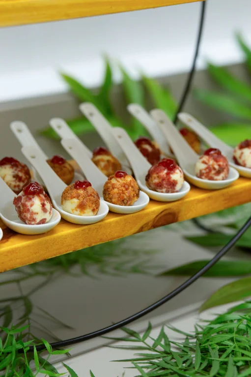 Fingerfood-Häppchen auf Porzellanlöffeln, angerichtet auf einem Holzbrett