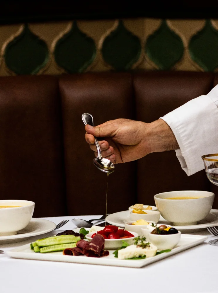 Hand träufelt Olivenöl über eine mediterrane Vorspeisenplatte im Restaurant